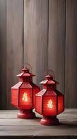 A vintage wooden table features two or three red lanterns, with room in the background for Chinese New Year text or a logo. photo