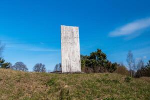 Weathered Stone Slab on Grassy Hill with Sparse Trees and Power Lines photo