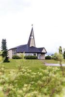 Small Church with Triangular Steeple and Paved Pathway on Cloudy Day photo