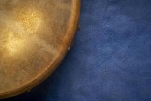 detail of handmade, native American style, shaman frame drum against textured art paper photo