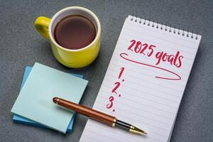 2025 goals list in a notebook with pen and coffee, setting New Year goals and resolutions photo