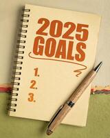 2025 goals list in a notebook with pen, setting New Year goals and resolutions photo