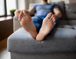 Lazy Day at Home. Man Relaxing on Comfortable Grey Sofa photo