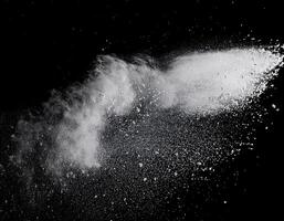 such as flour, splashing or sifting through the air against a stark black background. photo