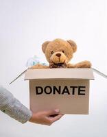 Charitable Gesture, Box with 'Donate' Label and Doll Inside, Held in Hands photo