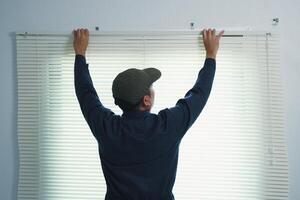 A curtain installer is installing curtains at a customer's house. Window in a room. photo