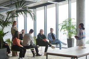 A diverse group of business professionals sits attentively in a modern office, actively participating in a training session led by an instructor, focusing on the latest technological advancements in photo
