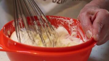 Hand Whisking Creamy Mixture in Bright Orange Mixing Bowl video