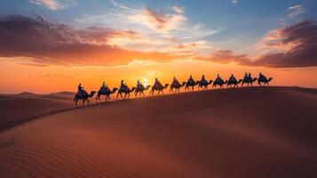 Camel Caravan Crossing Desert Dunes at Sunset. photo