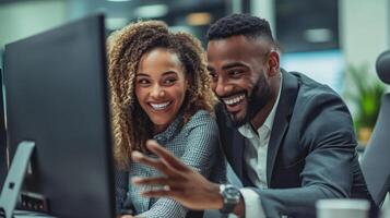 Two smiling colleagues working together on a computer in an office photo
