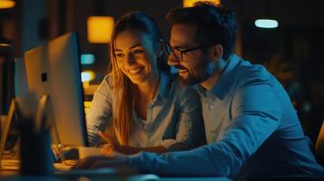 A Couple Collaborating on a Project, Working Together on a Computer in a Dimly Lit Office Setting photo