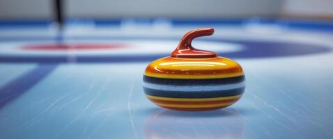 A vibrant curling stone rests on the smooth blue ice of a rink photo