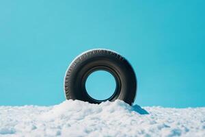 Tire partially buried in snow against a clear blue sky during winter daytime photo
