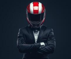 Stylish racer in a suit stands confidently with arms crossed, showcasing a striking red and white helmet photo