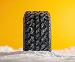 Tire on snow with a bright yellow background showcasing its intricate tread design and performance capabilities photo