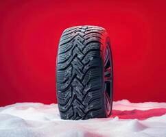 High-performance winter tire showcased against a vibrant red background with snow accents highlighting its capabilities photo