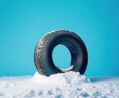 Snow-covered tire on a bright blue background in winter setting with vivid contrasts and clear textures showcased photo