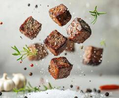 Delicious meat cubes floating in a burst of herbs and spices against a neutral background with garlic and salt photo
