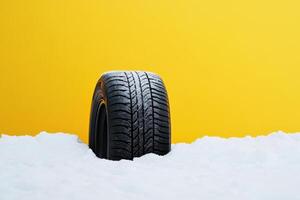 Snow-covered tire against bright yellow background showcasing winter conditions in an urban environment photo