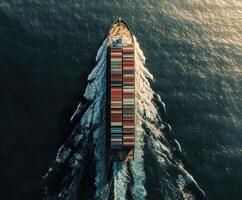 Container ship sails through open waters, creating waves under the setting sun photo