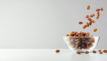 Cascading raisins falling from glass bowl, creating dynamic and appetizing scene. warm tones of raisins contrast beautifully with minimalist background photo