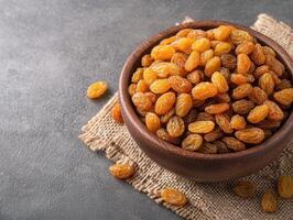 bowl of golden raisins on burlap cloth, showcasing their rich texture and color. Perfect for snacking or adding to recipes, these dried fruits offer sweet and nutritious option photo
