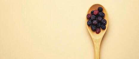 wooden spoon filled with dried raisins and cranberries on light background, showcasing simple yet appealing presentation of healthy snacks photo