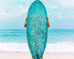 woman holding vibrant turquoise surfboard at beach, with waves in background, exuding sense of adventure and joy photo