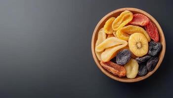 Dried tropical fruits in wooden bowl, showcasing vibrant colors and textures. This healthy snack option is perfect for adding flavor to meals or enjoying on its own photo