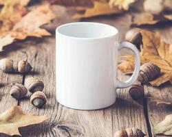 blank white mug surrounded by autumn leaves and acorns, creating cozy seasonal atmosphere perfect for warm beverages photo