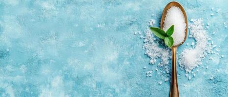 single spoon of salt with fresh mint leaves on blue background creates refreshing and clean aesthetic. contrast of textures adds visual interest photo