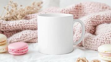 close up of blank white mug surrounded by pastel macarons and cozy knitted blanket, creating warm and inviting atmosphere. Perfect for showcasing beverage ideas or cozy settings photo