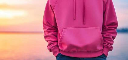 vibrant pink hoodie against serene sunset backdrop by water, showcasing casual and stylish look. warm colors evoke sense of calm and relaxation photo