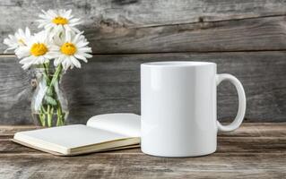 blank white mug sits on wooden table next to open notebook and vase of daisies, creating serene and inviting atmosphere for creativity photo