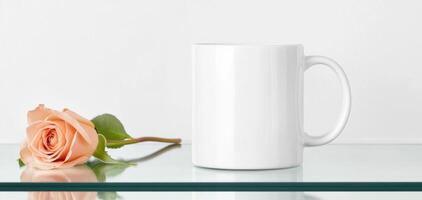 minimalist white mug placed on glass surface next to peach rose, creating serene and elegant atmosphere. Perfect for showcasing beverages or gifts photo