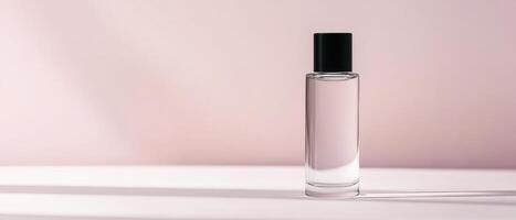 Clear glass perfume bottle with black cap on soft pink background, showcasing elegance and simplicity. light creates gentle shadow, enhancing its modern design photo