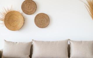 cozy living room featuring neutral sofa adorned with soft cushions, complemented by decorative woven wall art. warm tones create serene atmosphere photo