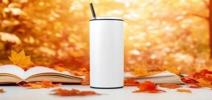 white tumbler stands on table surrounded by autumn leaves and open books, evoking cozy fall atmosphere perfect for enjoying warm beverages photo