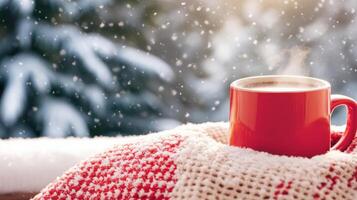 Warm red mug on cozy blanket with snowflakes falling in winter scene. serene atmosphere evokes feelings of comfort and relaxation during snowy season photo