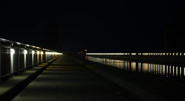 Long row of lights reflected on a river with street. photo