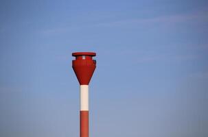 Modern red and white striped lighthouse on blue sky seen from an unusual wide angle directly from below. Rostock, Mecklenburg-Vorpommern, Germany photo