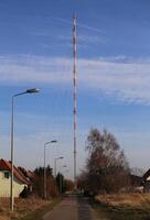 Small street leading to a red and white radio tower photo