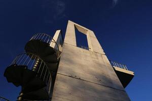 Lookout tower with spiral staircase seen from below. The sky is darkened due to the use of a polarization filter. photo