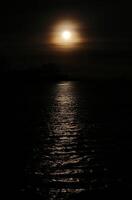 Dark high contrast shot of misty sun with reflections on the water. photo