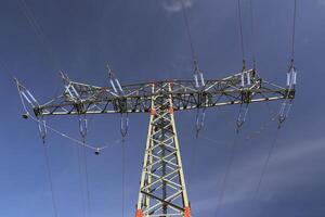 View of a high voltage line pylon and dark blue sky from below. photo