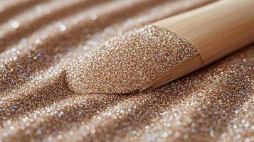 Fine golden particles shimmer on a textured surface, accentuated by a wooden applicator tool nearby photo