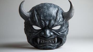 A striking demonic mask with sharp horns rests against a light backdrop, sparking curiosity photo