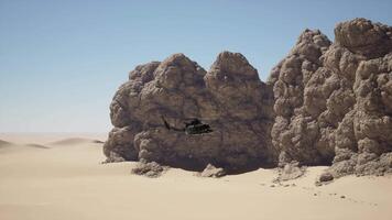 A helicopter flying over a desert with a rock formation in the background video