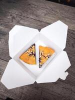 Two slices of blueberry pie resting in white cardboard box on rustic wooden table photo