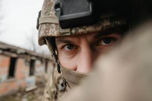 A soldier's intense gaze amid a war-torn landscape in a devastated building during a recent conflict photo